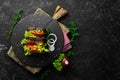 Homemade sandwich with toasted bread slices with sausage, onion, cheese and lettuce on a black stone background.