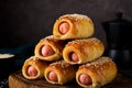 Homemade sausages in dough pigs in blanket on a wooden board, dark background