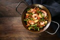 Homemade seafood dish with rice, prawns, chicken and vegetables in a Spanish paella pan on a dark rustic wooden table, copy space Royalty Free Stock Photo