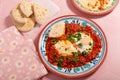 Homemade shakshuka breakfast topped with fresh herb leaves and garnished with flatbread