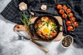 Homemade shakshuka, fried eggs, onion, bell pepper, tomatoes and parsley in a pan. Gray background. Top view