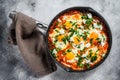 Homemade shakshuka, fried eggs, onion, bell pepper, tomatoes and parsley in a pan. Gray background. Top view