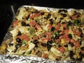 Homemade sheet pan loaded nachos with olives, fresh tomatoes, scallions, cheese, black beans, and meat Royalty Free Stock Photo