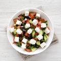 Homemade Shepards salad with cucumbers, feta and parsley in a white bowl on a white wooden background, top view. From above,