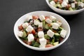 Homemade Shepards salad with cucumbers, feta and parsley in white bowls on a black background, side view. Close-up