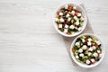 Homemade Shepards salad with cucumbers, feta and parsley in white bowls on a white wooden background, top view. From above,