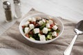 Homemade Shepards salad with cucumbers, parsley and feta in a white bowl on a white wooden background, side view. Closeup