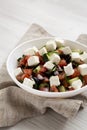 Homemade Shepards salad with cucumbers, parsley and feta in a white bowl on a white wooden surface, side view. Closeup