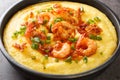 Homemade shrimp and grits with smoked bacon, onions and cheese in a black bowl on a dark concrete background. Horizontal