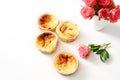 Homemade small curd cakes or muffins and pink roses on a white table with copy space, background fades to white
