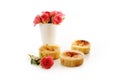 Homemade small curd cakes or muffins and a vase with pink roses isolated with shadows on a white background