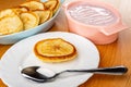 Small pancakes in bowl, soft cottage cheese with fruit in bowl, spoon and pancake in plate on wooden table