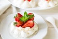 Homemade small strawberry pavlova meringue cakes with mascarpone cream and fresh mint leaves