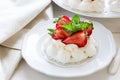 Homemade small strawberry pavlova meringue cakes with mascarpone cream and fresh mint leaves