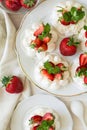 Homemade small strawberry pavlova meringue cakes with mascarpone cream and fresh mint leaves