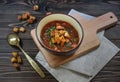 Homemade soup with auharics and herbs in a round plate stands on a wooden cutting board and a linen napkin. Royalty Free Stock Photo