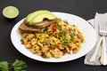 Homemade southwestern egg scramble with toast on a white plate on a black background, low angle view. Close-up