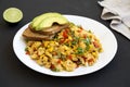 Homemade southwestern egg scramble with toast on a white plate on a black surface, low angle view. Close-up