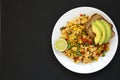 Homemade southwestern egg scramble with toast on a white plate on a black surface, top view. Flat lay, overhead, from above. Copy