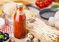 Homemade spaghetti pasta with quail eggs with bottle of tomato sauce and cheese on wooden background. Classic italian village food