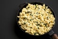 Homemade Spinach Mac and Cheese in a cast-iron pan on a black background, side view. Space for text Royalty Free Stock Photo