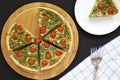 Homemade Spinach Quiche on a round bamboo board on a black background, top view. Flat lay, overhead, from above Royalty Free Stock Photo