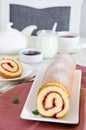 Homemade sponge cake with raspberry jam on a white plate on a white wooden dining table. Royalty Free Stock Photo