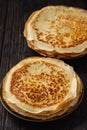 Homemade stack of crepes, on dark wooden background.