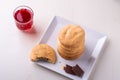 Homemade stack of shortbread chocolate cookies with one bitten cookie and two pieces of chocolate on white plate with stewed fruit