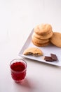 Homemade stack of shortbread chocolate cookies with one bitten cookie and two pieces of chocolate on white plate with stewed fruit