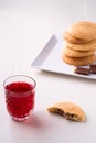 Homemade stack of shortbread chocolate cookies with one bitten cookie and two pieces of chocolate on white plate with stewed fruit