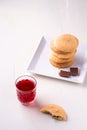 Homemade stack of shortbread chocolate cookies with one bitten cookie and two pieces of chocolate on white plate with stewed fruit