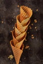 Homemade stacked empty cornets or ice cream waffle cones on dark background. Selective focus. Minimal flat lay composition with co