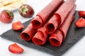 Homemade strawberry fruit leather on black slate closeup