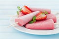 Homemade strawberry ice cream or popsicles in plate on blue wooden table, frozen fruit juice Royalty Free Stock Photo