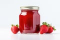 A homemade strawberry jam in a glass jar, set against a white background