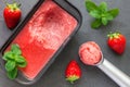 Homemade strawberry sorbet in tray on a gray slate