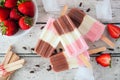 Homemade strawberry vanilla chocolate neapolitan yogurt popsicles over rustic white wood Royalty Free Stock Photo