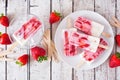 Homemade strawberry vanilla yogurt popsicles, top view scene on rustic white wood Royalty Free Stock Photo