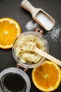 Homemade sugar body scrub in glass jar, with fresh orange. slices and wooden spoon with sugar powder on black stone cutting board. Royalty Free Stock Photo
