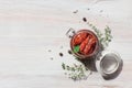 Homemade sun-dried tomatoes in oil with fresh herbs thyme, oregano in a glass jar on a light wooden background Royalty Free Stock Photo