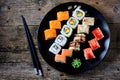Homemade sushi with salmon, tobiko caviar, omelet, cucumber, sesame and soft cheese on old wooden background. Rustic style. Royalty Free Stock Photo