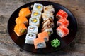 Homemade sushi with salmon, tobiko caviar, omelet, cucumber, sesame and soft cheese on old wooden background. Rustic style. Royalty Free Stock Photo