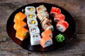 Homemade sushi with salmon, tobiko caviar, omelet, cucumber, sesame and soft cheese on old wooden background. Rustic style. Royalty Free Stock Photo