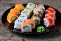 Homemade sushi with salmon, tobiko caviar, omelet, cucumber, sesame and soft cheese on old wooden background. Rustic style. Royalty Free Stock Photo