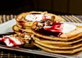 Homemade sweet pancakes with fruit jam, sour cream on a white plate. Breakfast with stack topped blueberry jam and Royalty Free Stock Photo