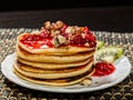 Homemade sweet pancakes with raspberry jam on a white plate. Breakfast with stack topped blueberry jam, walnuts and kiwi Royalty Free Stock Photo
