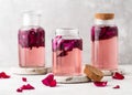 Homemade sweet rose water or syrup in glass bottles with pink petals in it. Healthy summer food concept. Royalty Free Stock Photo