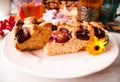 Homemade sweet round plum cake New York Times cuts on plate with cups, glasses of tea, coffee, flowers at back side on holyday Bre Royalty Free Stock Photo