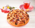 Homemade sweet round plum cake New York Times on plate with herbal tea cup and flowers on family Breakfast or birthday holyday par Royalty Free Stock Photo